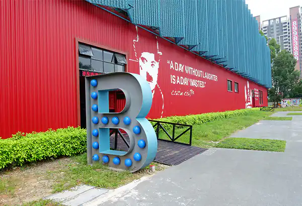 Rote Gebaeudefassade mit grossem Buchstabenobjekt und Gehweg davor